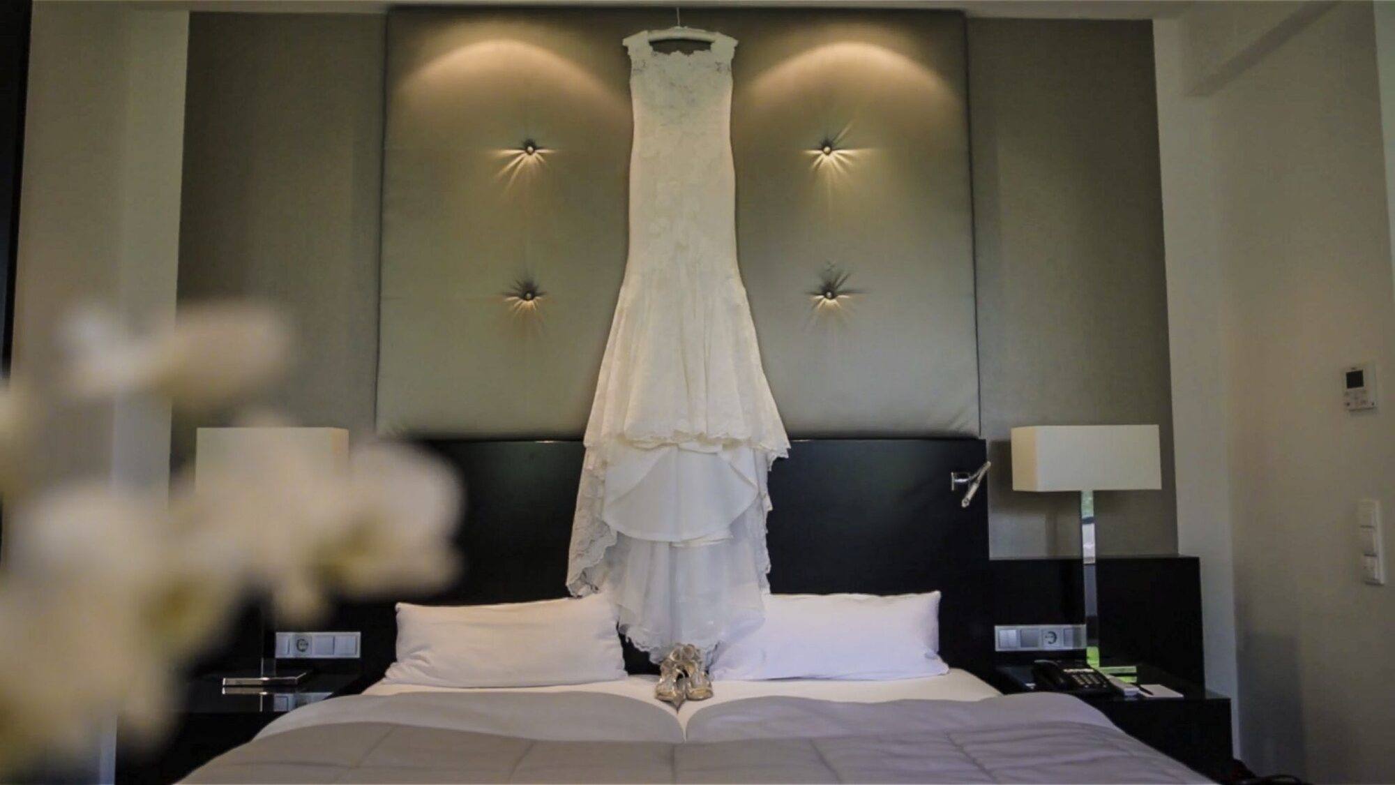 Brautkleid hängt im Hotelzimmer über dem Bett, Hochzeit im Rheingau