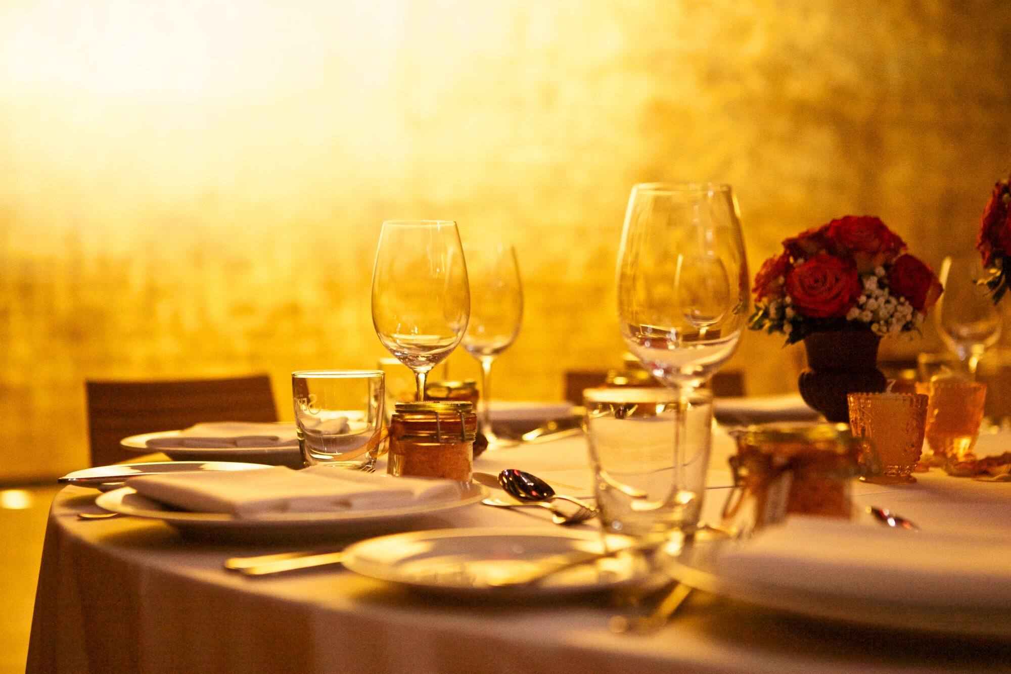 Gedeckte Tafel mit Weingläsern und Rosen vor der goldenen Wand im Goldbergwerk Fellbach