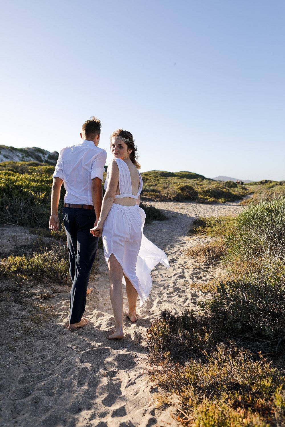 Diana und Tim gehen auf einem Sandpfad durch die Dünen bei Kapstadt