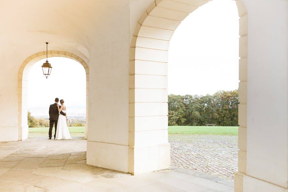 Brautpaar unter den Arkaden von Schloss Solitude mit Blick ins Grüne