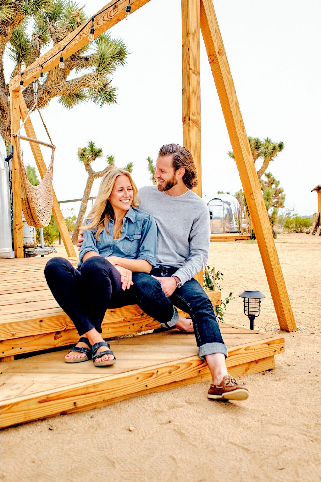 Paar sitzt eng beieinander auf der Holzterrasse des Airstream-Camps