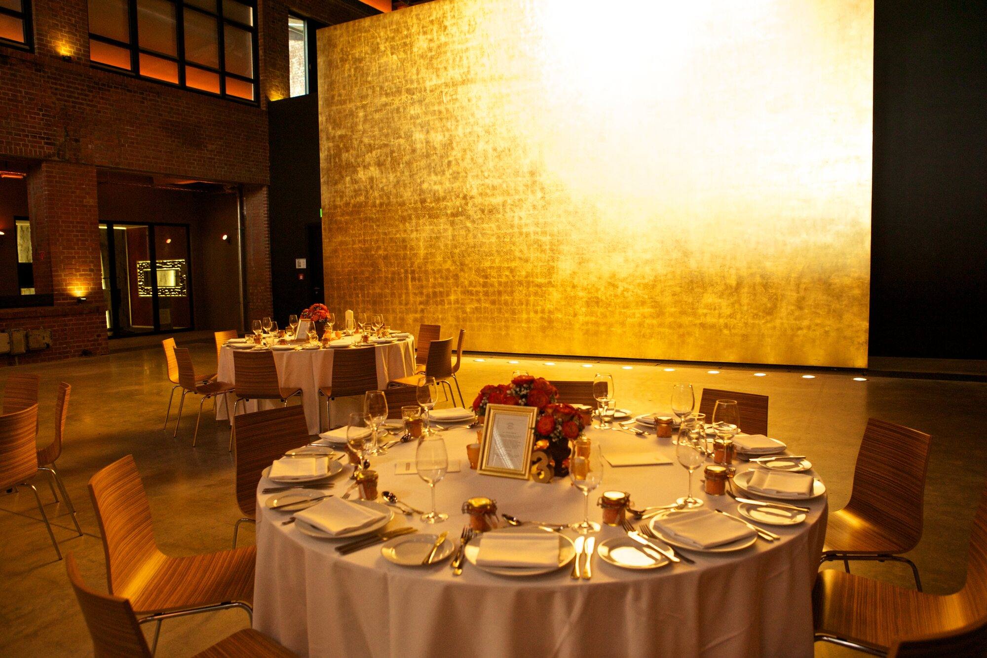Runde Hochzeitstafel vor der beleuchteten goldenen Wand im Goldbergwerk Fellbach