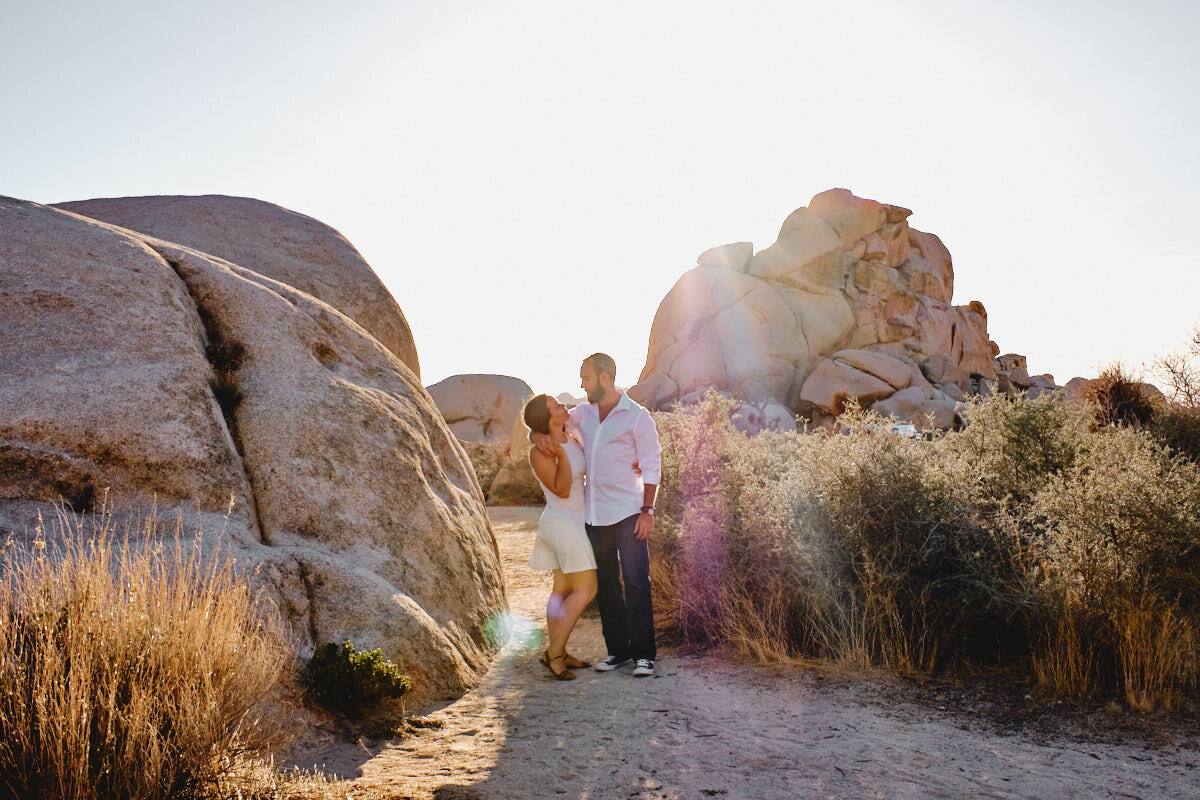 Liz und Ron zwischen Felsblöcken und Wüstengras im Abendlicht, Joshua Tree