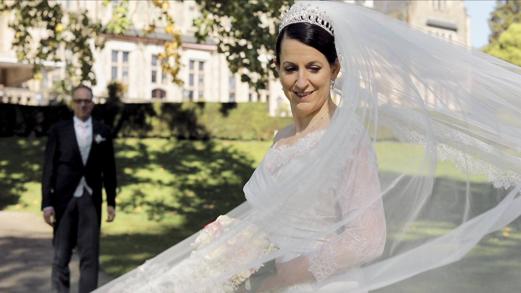 Bräutigam nähert sich der Braut im Park, Schleier im Wind, Schlosshotel Kronberg