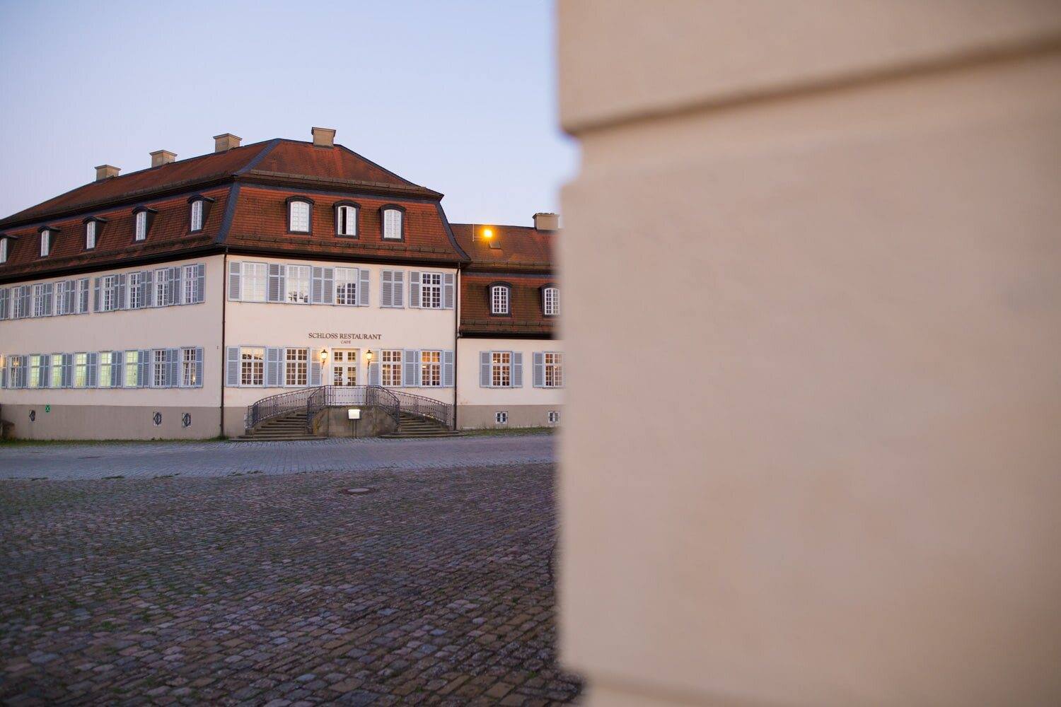 Kavaliersbau von Schloss Solitude am Abend, gerahmt von einer Mauerkante
