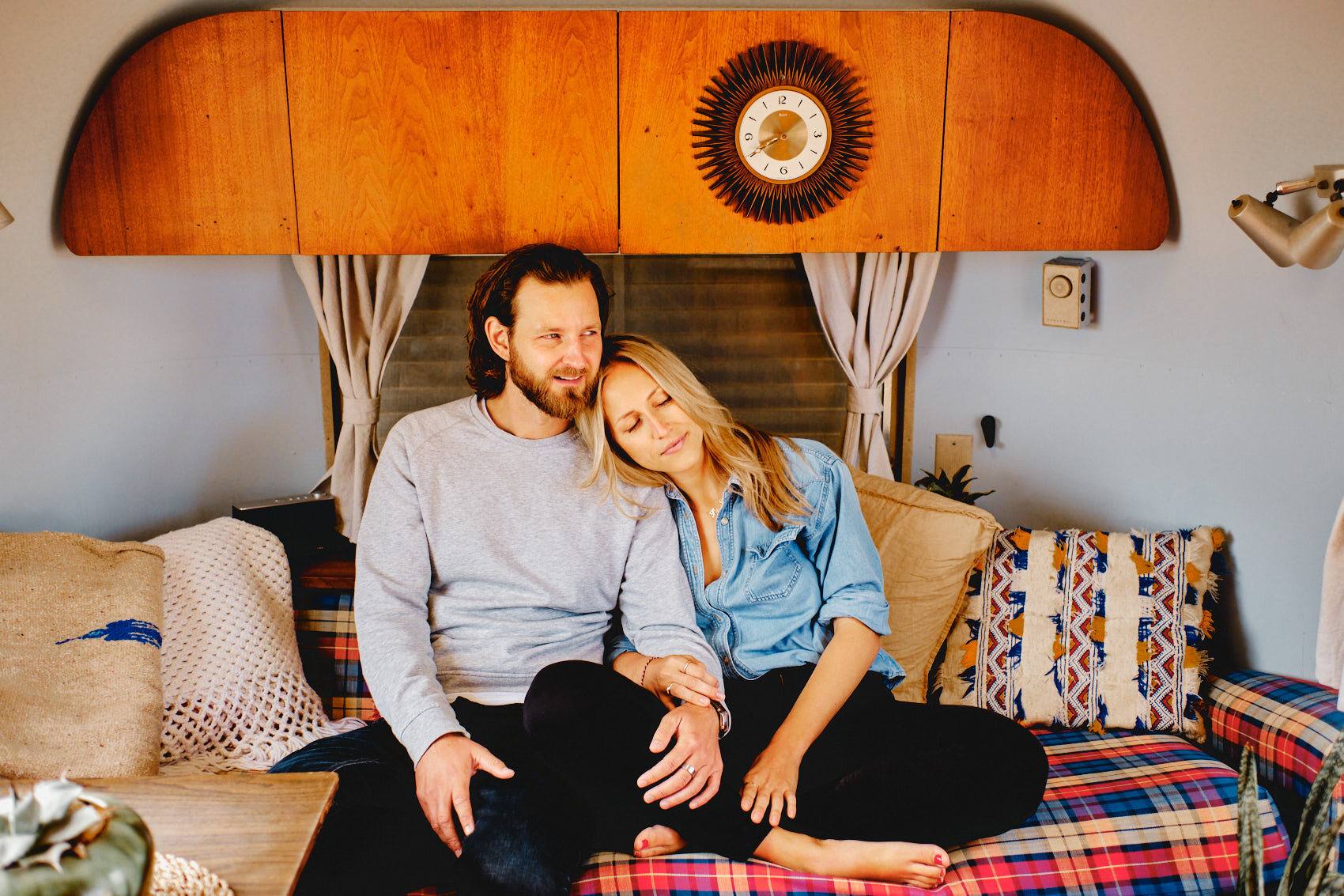 Paar kuschelt im Vintage-Airstream vor holzverkleideter Wand