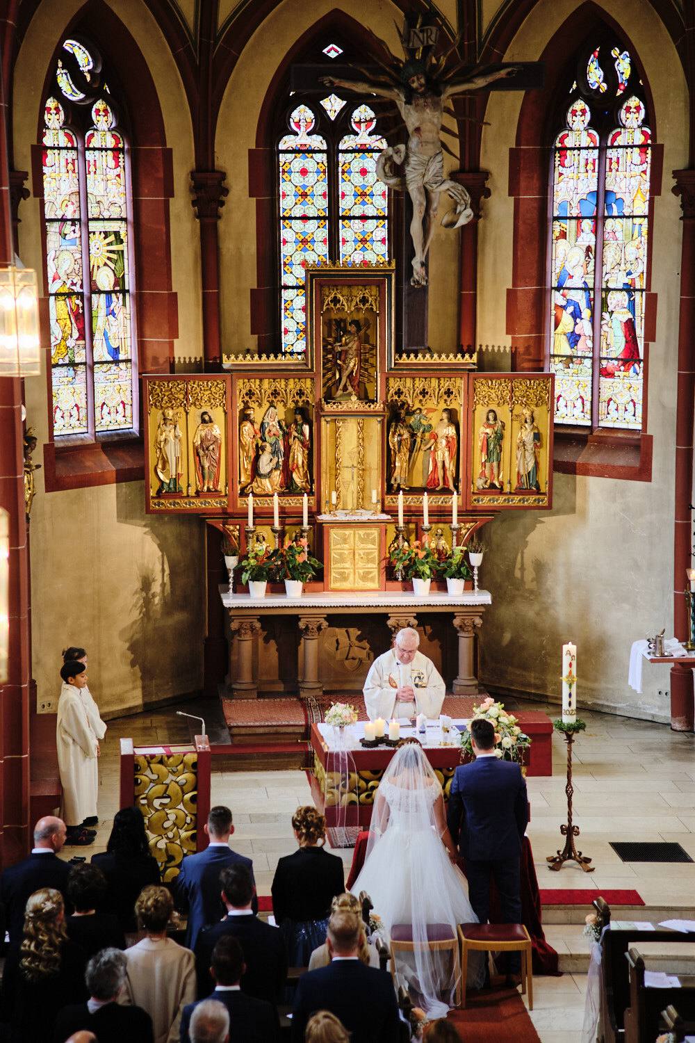 Vergoldeter Flügelaltar mit bunten Glasfenstern, das Brautpaar davor