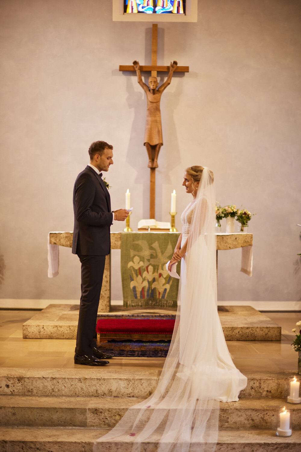 Brautpaar steht vor dem Altar mit langem Schleier.