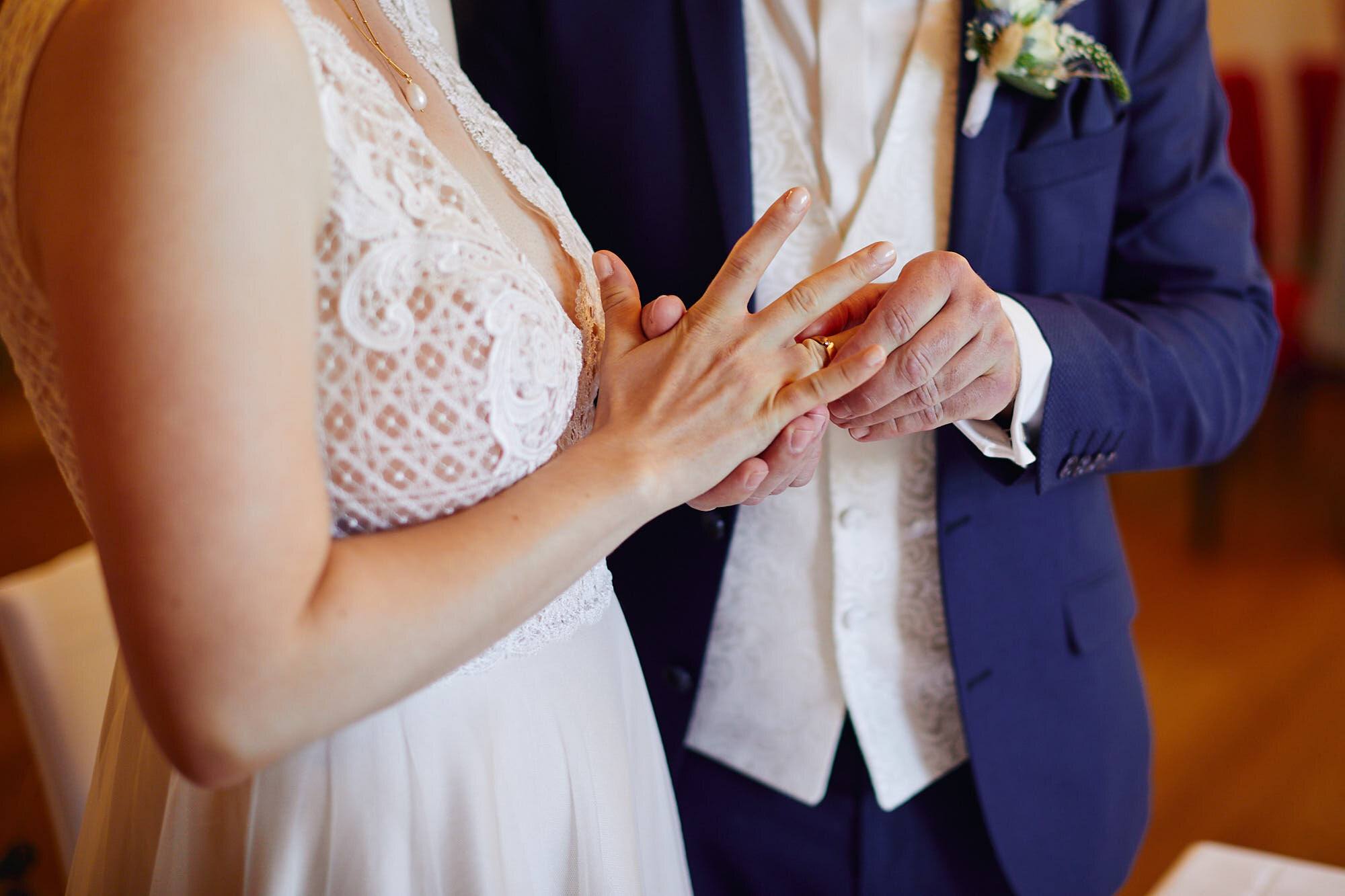Ringtausch: Hände mit Spitzenärmel und royalblauem Anzug