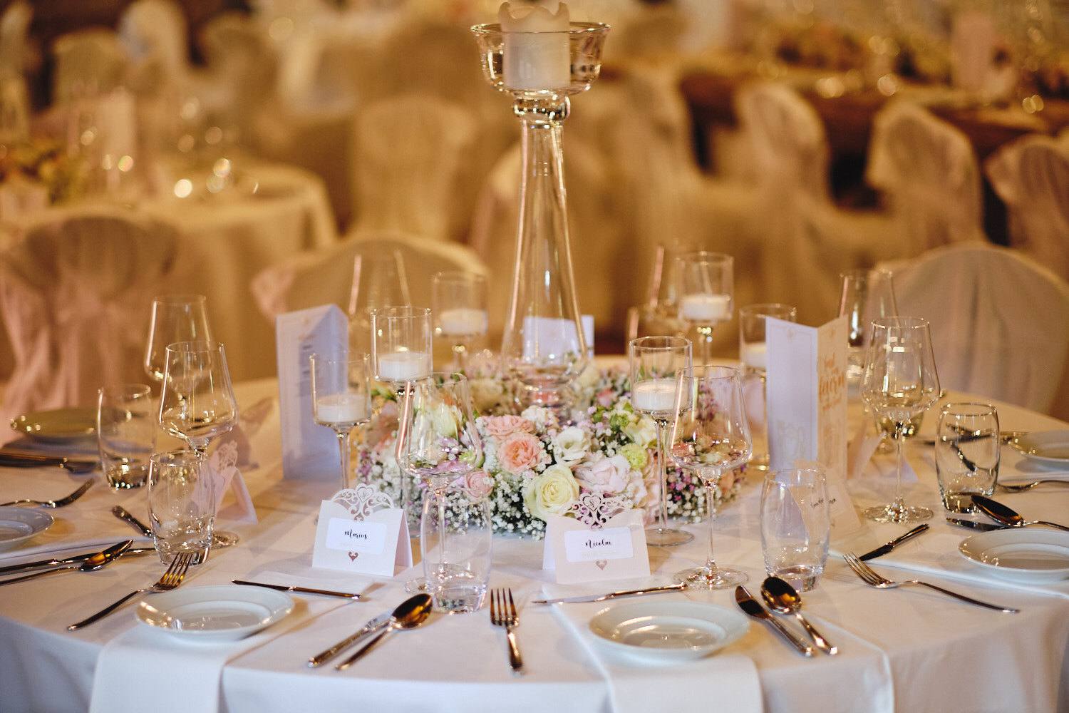 Gedeckter Tisch mit Blumen und Kerzenständern.