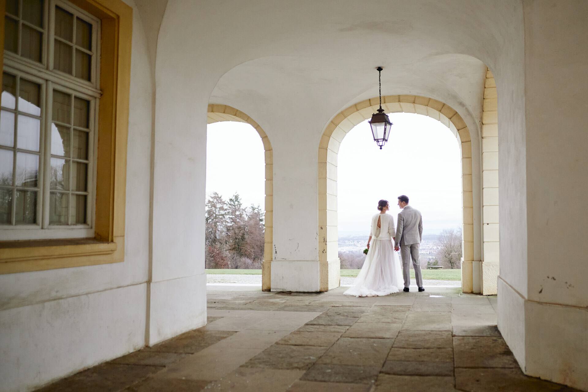 Brautpaar unter den Arkaden von Schloss Solitude mit Blick in die Weite
