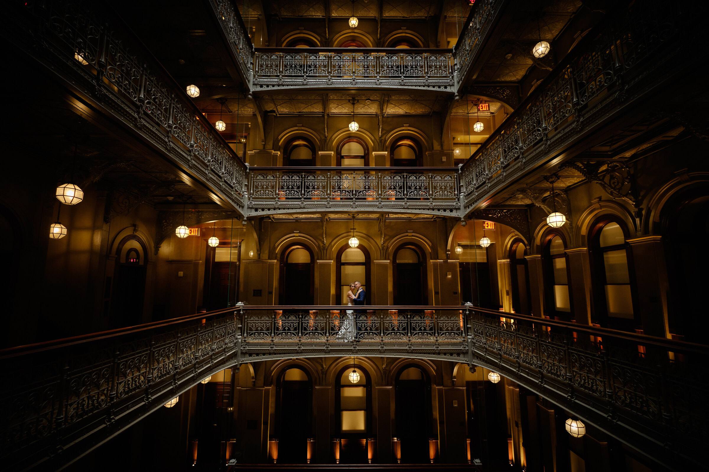 Brautpaar klein auf einer Galerie in einem historischen Innenhof mit gusseisernen Galerien, New York
