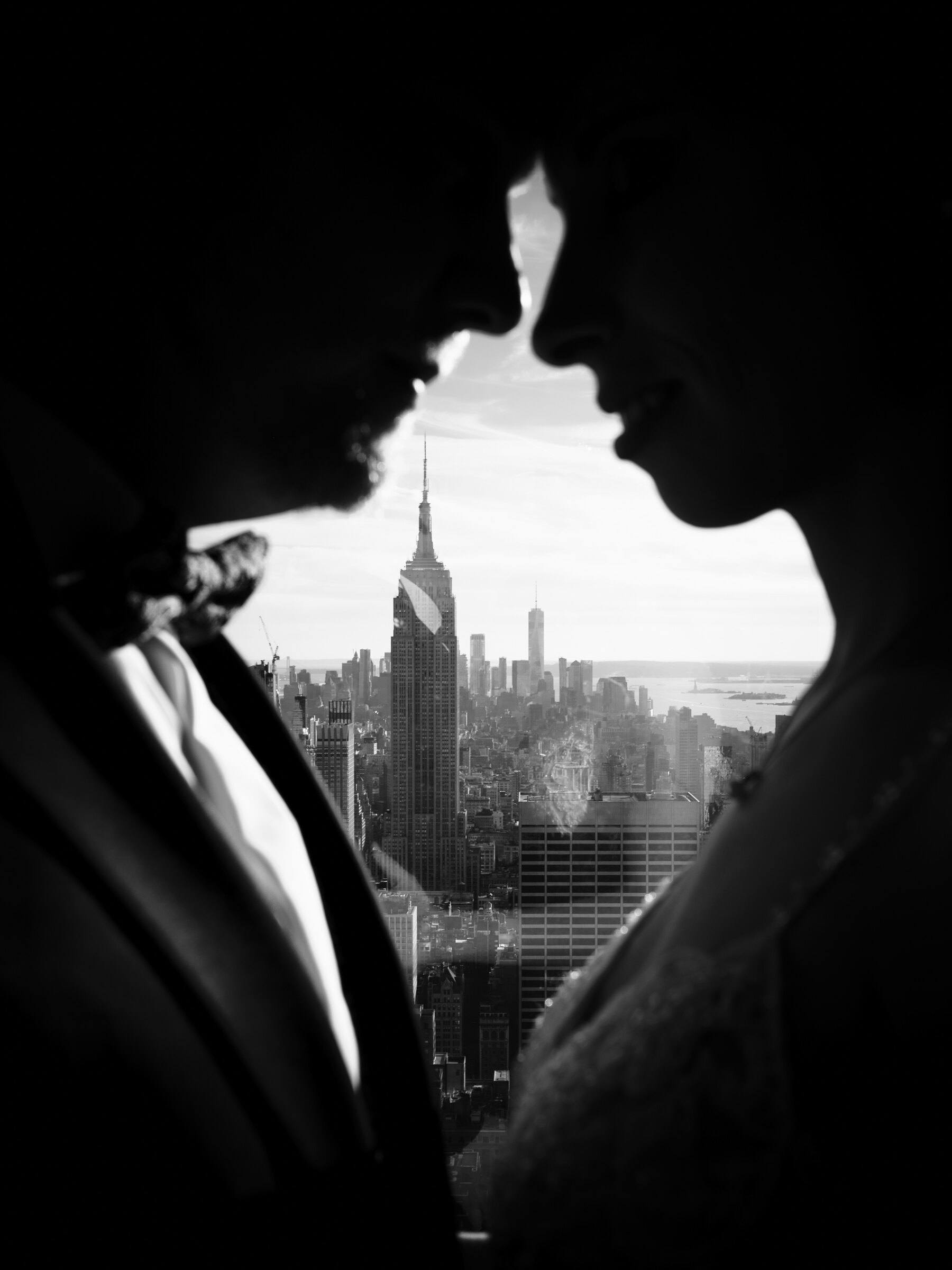 Schwarz-Weiß-Silhouette des Brautpaars Nase an Nase, dazwischen die Skyline von New York