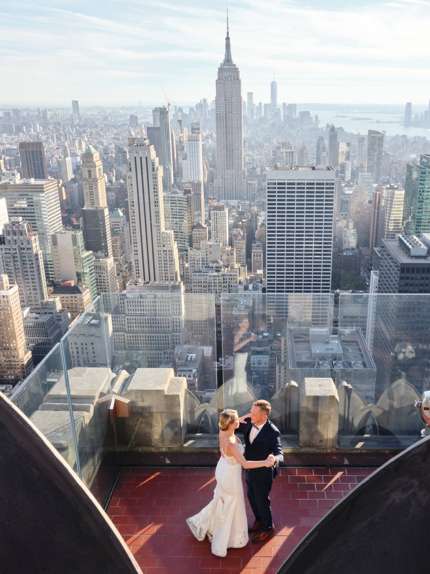 Brautpaar tanzt auf einer Aussichtsplattform über New York, dahinter das Empire State Building