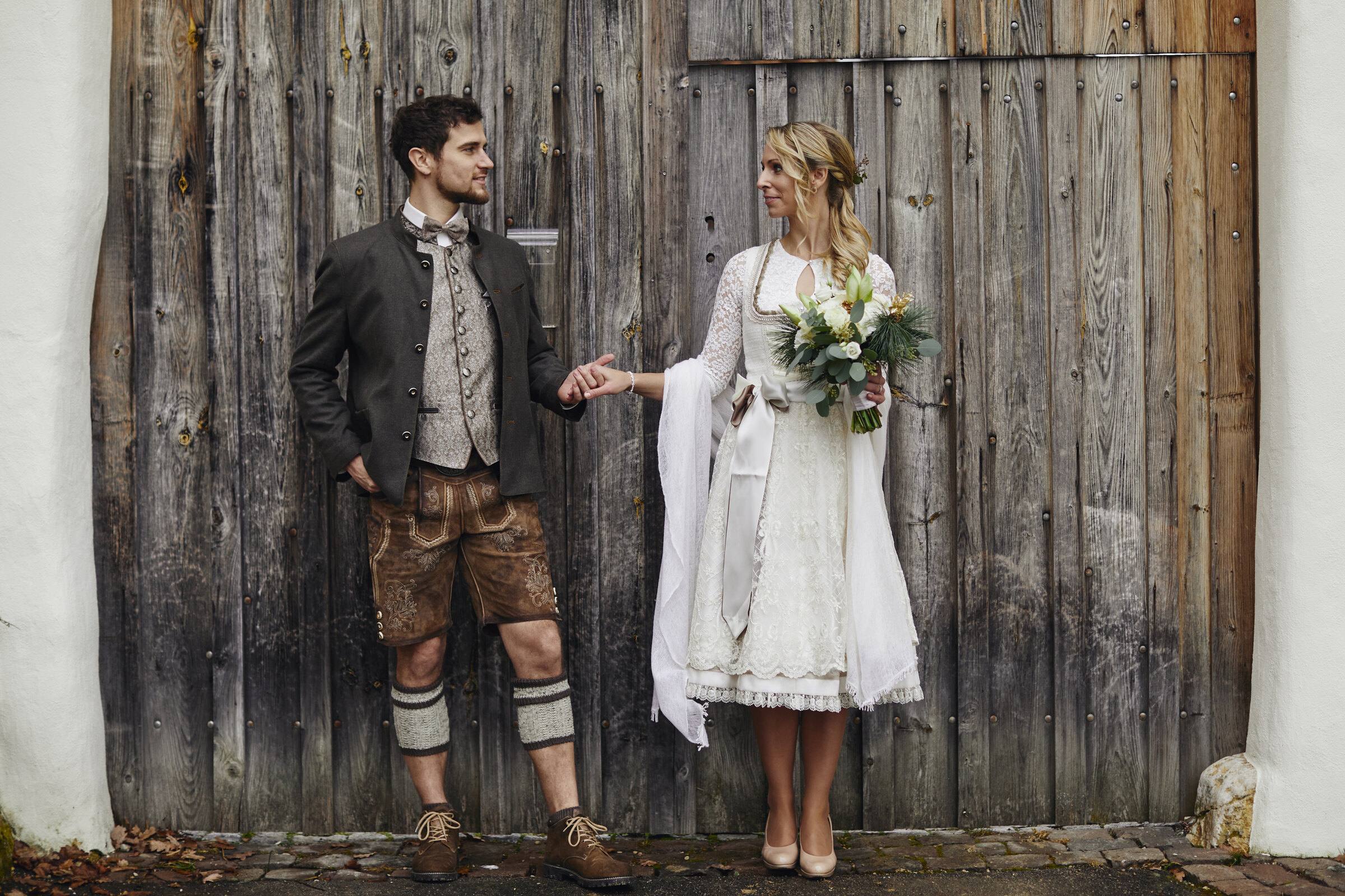 Brautpaar in Tracht vor einem Scheunentor.