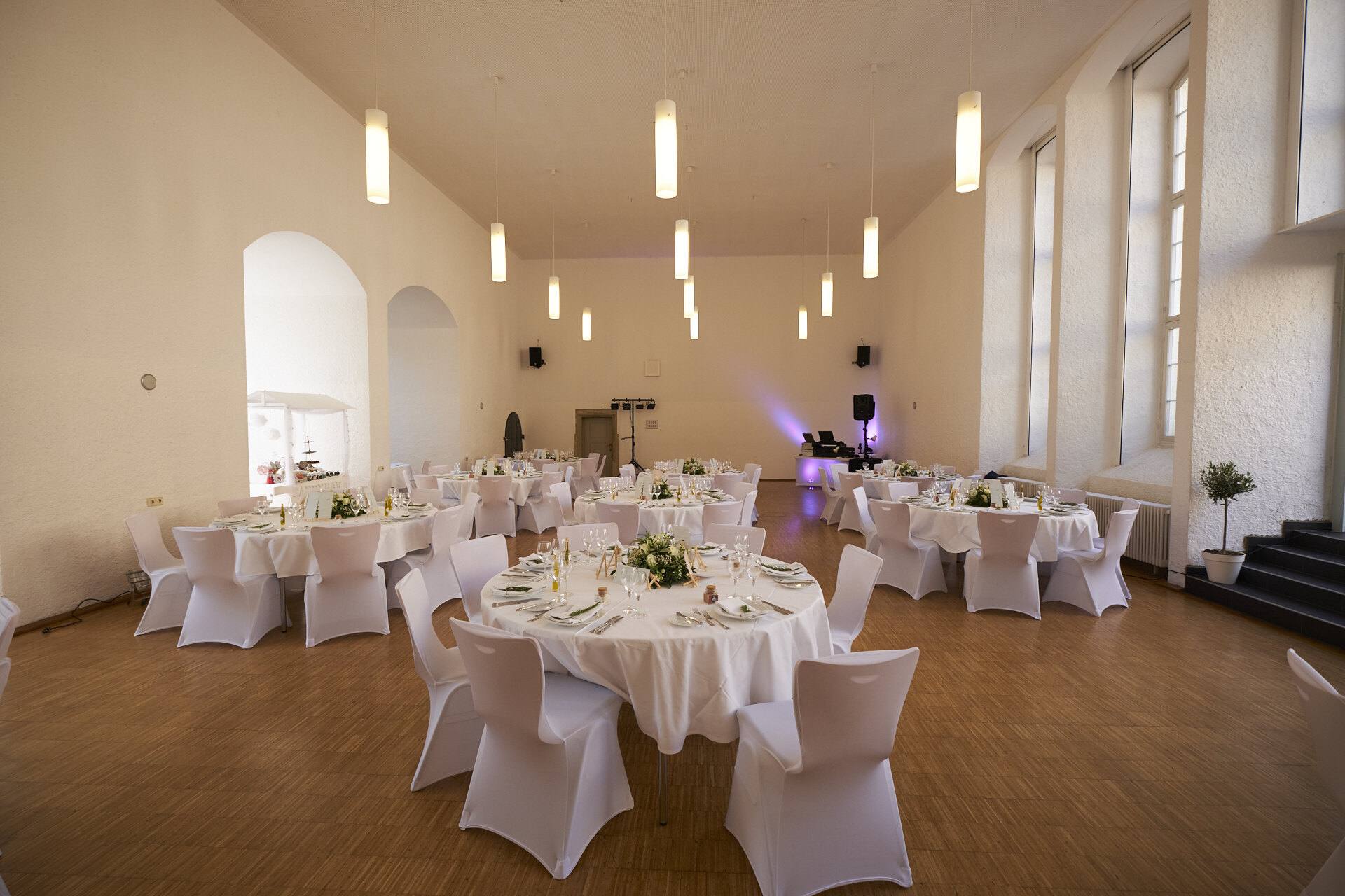 Festlich gedeckter Hochzeitssaal mit weißen Tischen.