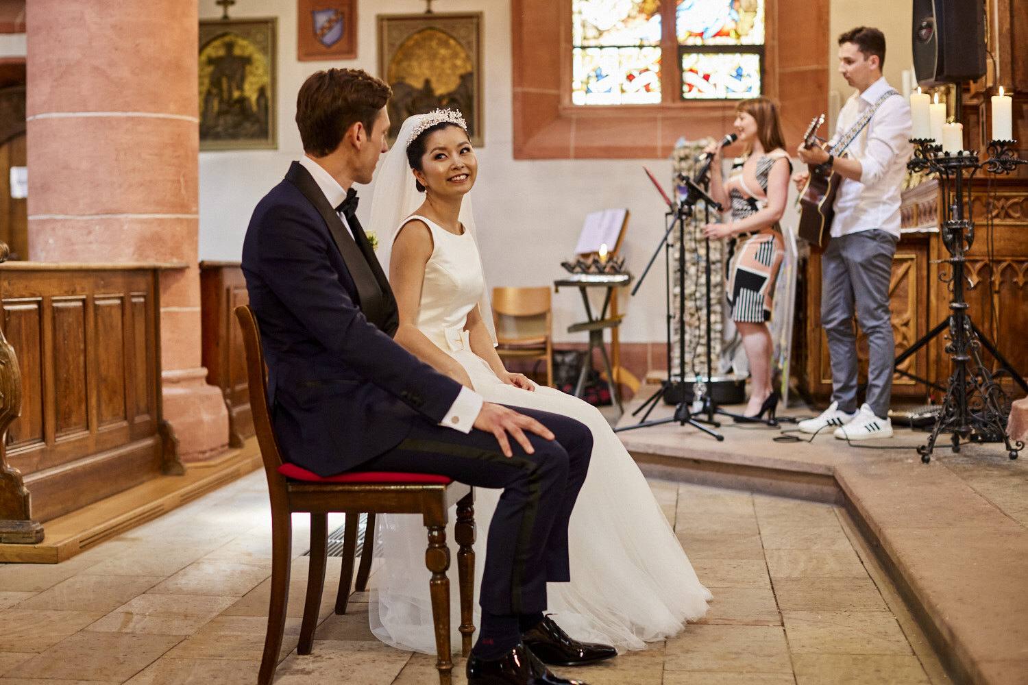 Brautpaar sitzt vor dem Altar, dahinter musizieren Sängerin und Gitarrist