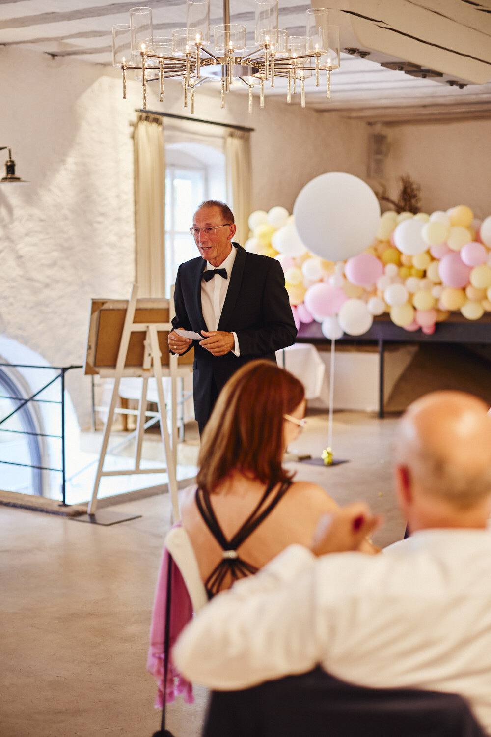 Ein Gast hält eine Rede vor einer Ballongirlande.