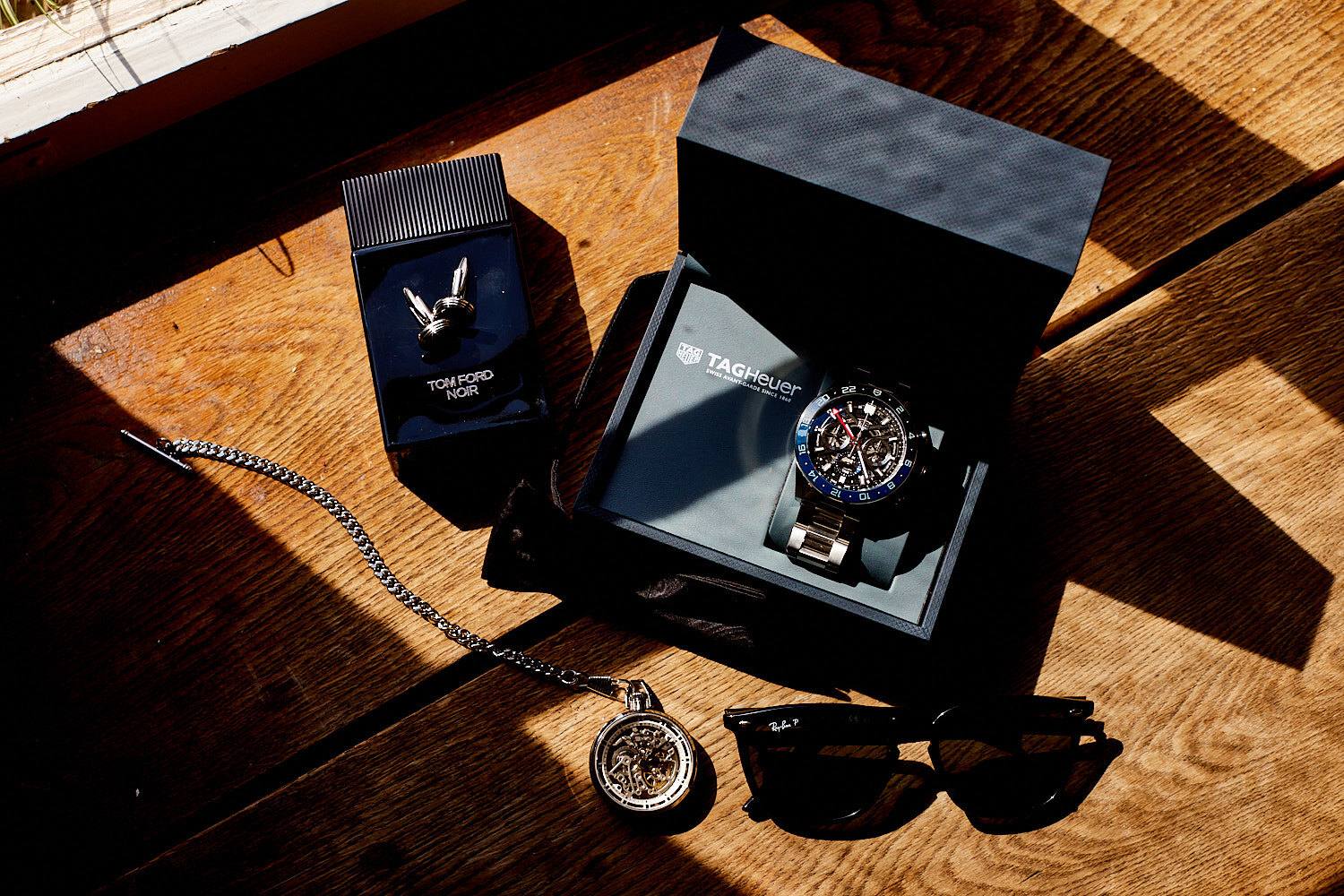 Herrenuhr, Taschenuhr und Sonnenbrille auf Holztisch.