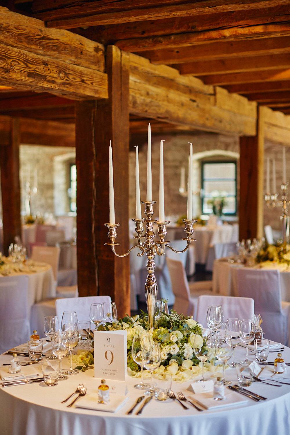 Gedeckter Hochzeitstisch mit Kerzenleuchtern und Blumen.