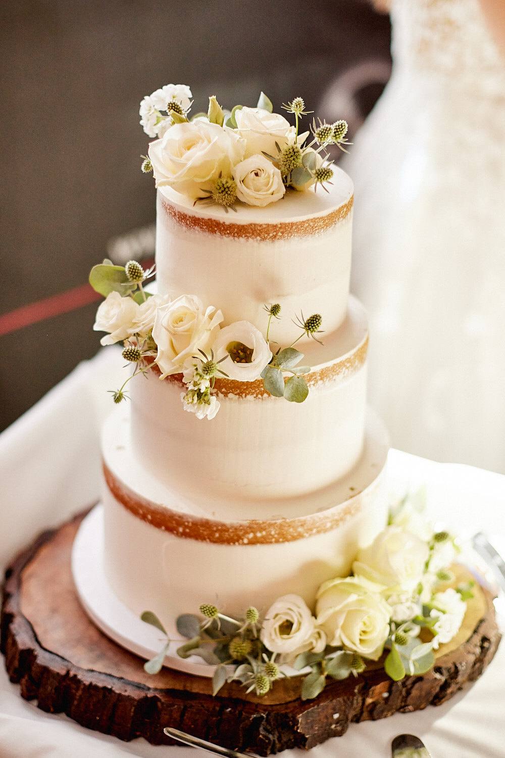 Naked Cake mit weißen Rosen auf einer Baumscheibe.